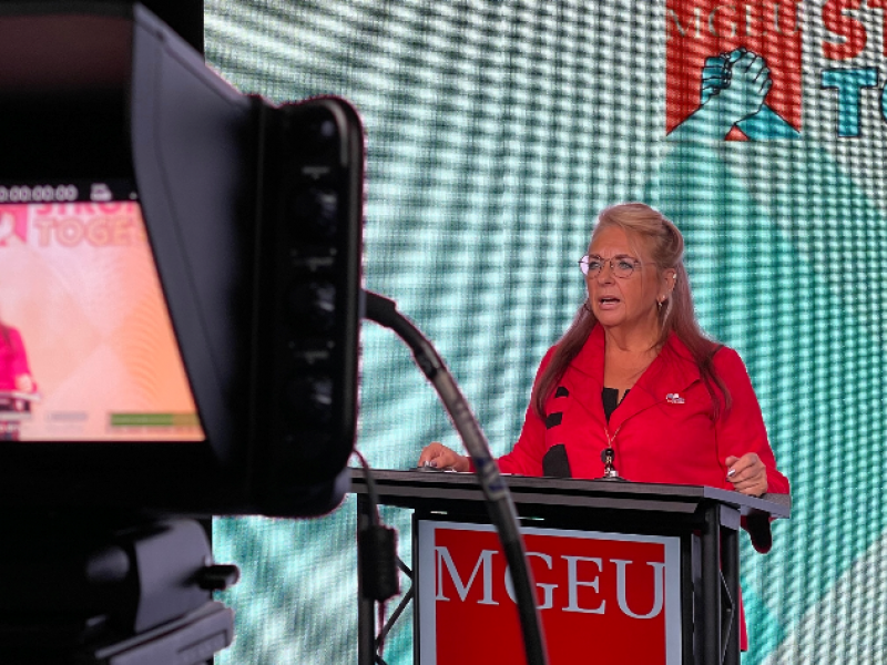 Michelle Gawronsky wearing red blazer standing behind podium in front of camera